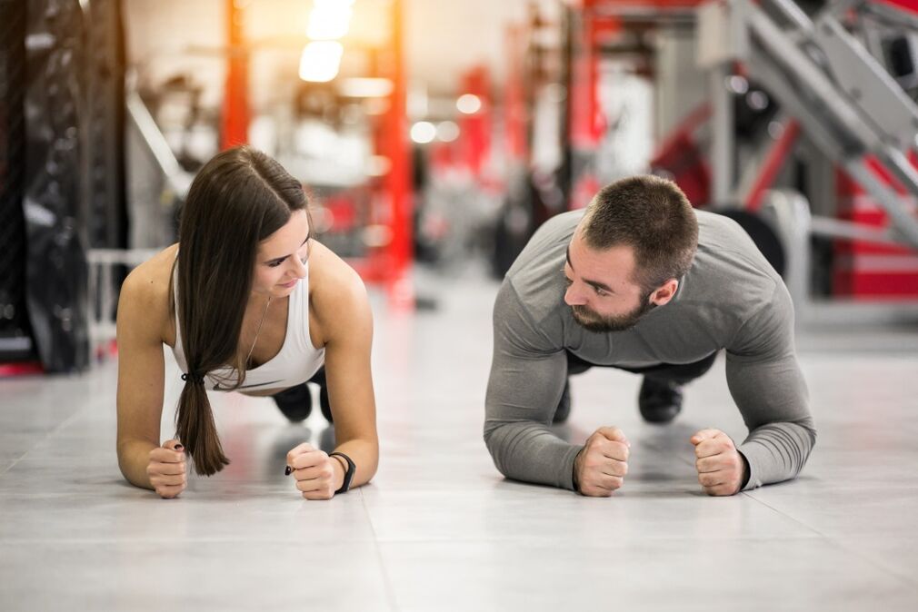 Un hombre y una mujer hacen el ejercicio Plank, que está diseñado para todos los grupos musculares